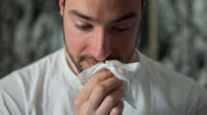 man with seasonal allergies holding tissue